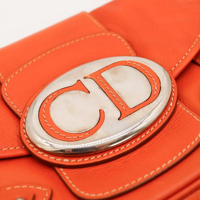 Détail plaque ovale CD argentée sur cuir rouge Dior — AMANA Vintage