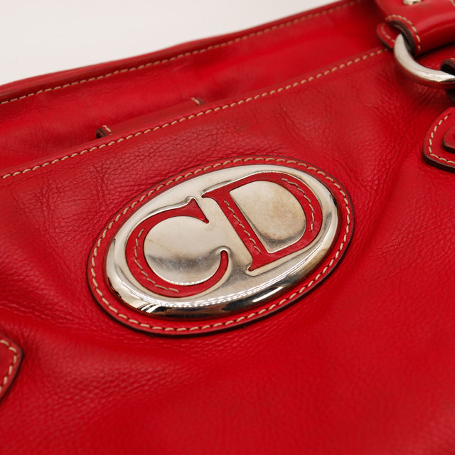 Détail plaque CD argentée sac Dior cuir rouge occasion authentique — AMANA Vintage