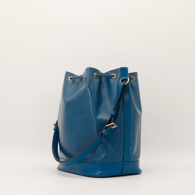 Vue de trois quarts Louis Vuitton Noe Epi bleu cordelette et oeillets dores — AMANA Vintage