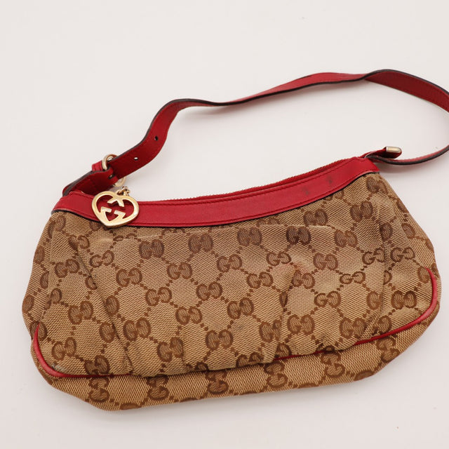 Détail breloque dorée Gucci interlocking sur pochette monogramme rouge — AMANA Vintage