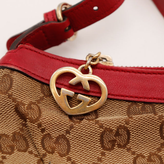 Détail breloque Gucci dorée ternie sur cuir rouge — AMANA Vintage