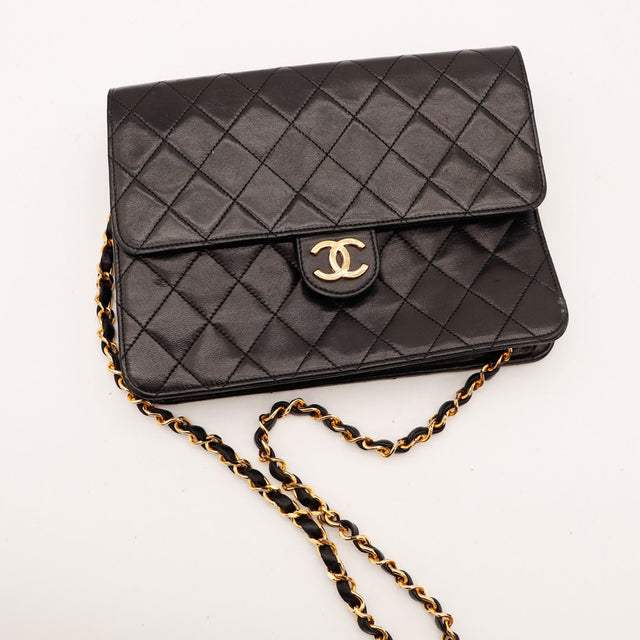 Sac Chanel Timeless noir posé vue de dessus cuir matelassé chaîne dorée — AMANA Vintage