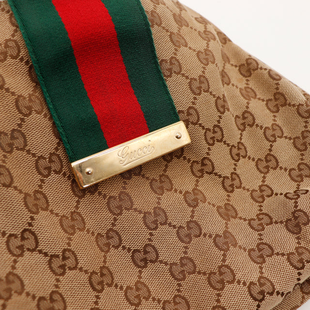 Detail plaque logo Gucci doree et ruban Web vert rouge occasion — AMANA Vintage